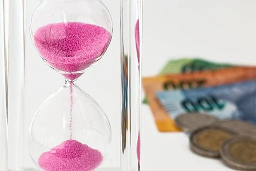 hourglass pink sand and money