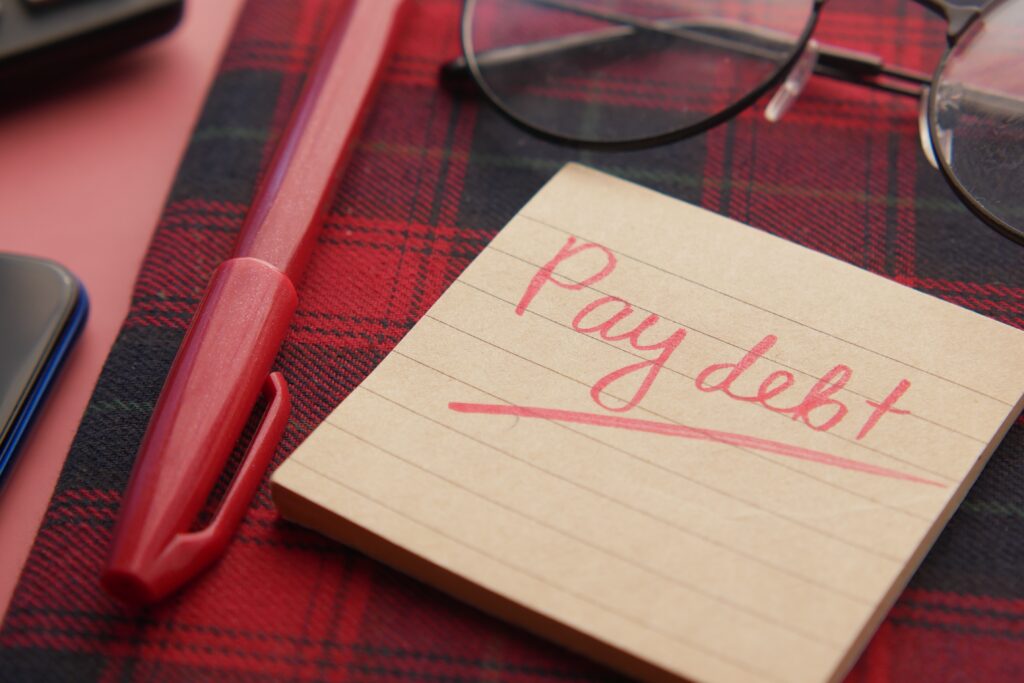 Post-it  with Pay Debt text on desk