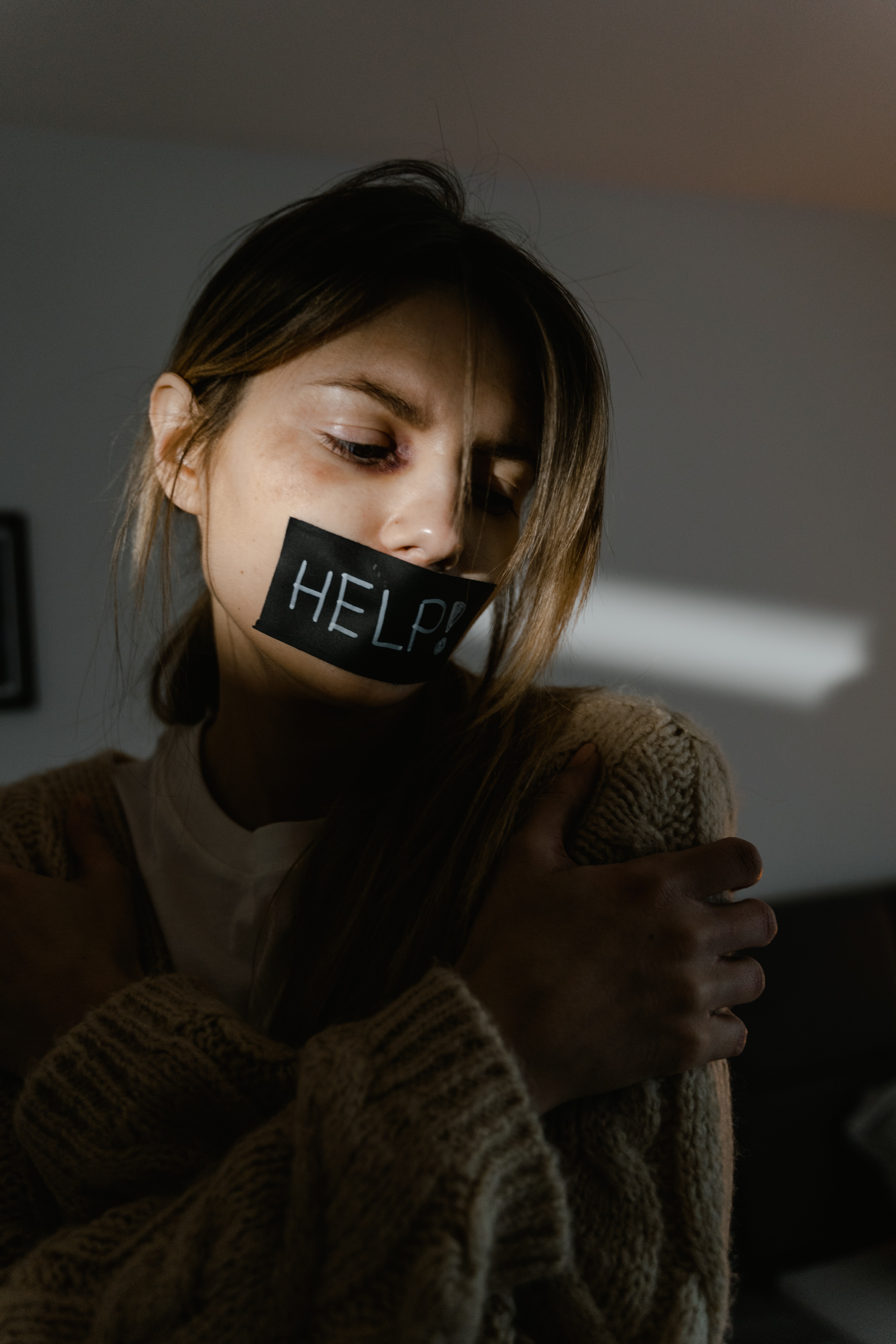 Woman with Help sign taped over her mouth